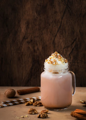Winter hot dark chocolate with whipped cream and crushed walnuts in glass jar, copy space