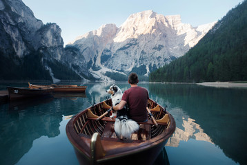 man and dog in a boat on a mountain lake. Trip with a pet to Italy. Australian Shepherd Dog and its owner