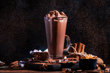 Glass of hot chocolate cocoa drink sprinkled with cocoa powder. Dark background. Winter food and drink concept with Copy space