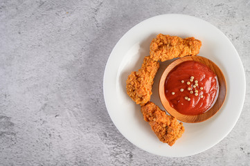 Crispy fried chicken on a white plate with tomato sauce, Top view.