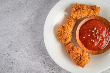 Crispy fried chicken on a white plate with tomato sauce, Top view.