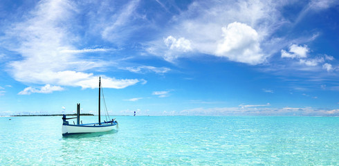 Boat in turquoise ocean water against blue sky with white clouds. Natural landscape for summer vacation. - Powered by Adobe