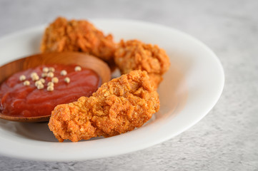 Crispy fried chicken on a white plate with tomato sauce, selective focus.