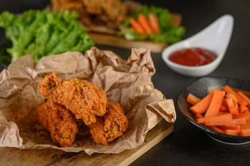 Crispy fried chicken on a cutting board with tomato sauce and carrot, Selective focus.