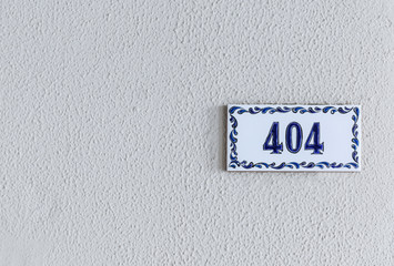 Mediterranean style house number 404 on a white and blue tile against a seamless speckled background.