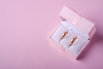Wedding gold rings in pink gift box on soft pink background, angle view, copy space