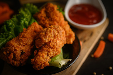 Crispy fried chicken on a cutting board with tomato sauce and carrot, Selective focus.