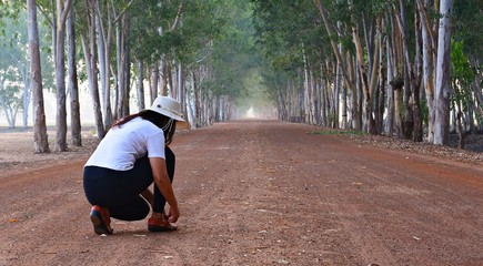 Asian women Wearing a white shirt and shoes tied on the road.