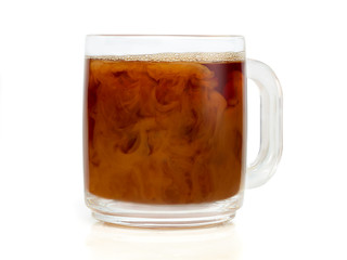 Closeup of cream mixing with coffee in a clear coffee cup with foam on top of the coffee