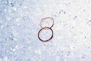 Two golden wedding rings on ice.