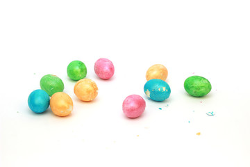 Multi-colored eggs with a broken shell lie on a white background. Easter holiday concept