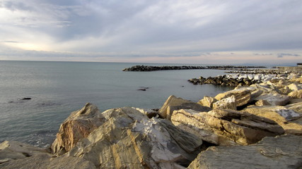 beautiful pastel view of the rocky beach and slightly cloudy sky on a quiet day by the sea