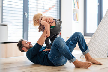 Father with small boy playing indoors in bedroom, having fun.