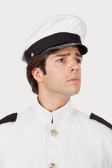 Young navy officer looking away against gray background
