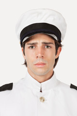 Portrait of young sad navy officer against gray background