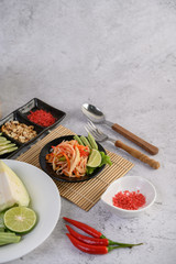 Thai papaya salad in a white plate with Spoon, fork, and dried shrimp.