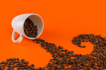 Coffee in a white cup on an orange background with coffee beans.