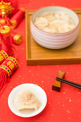 A bowl of shrimp wontons on red background for Chinese New Year