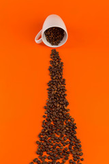 Coffee in a white cup on an orange background with coffee beans.