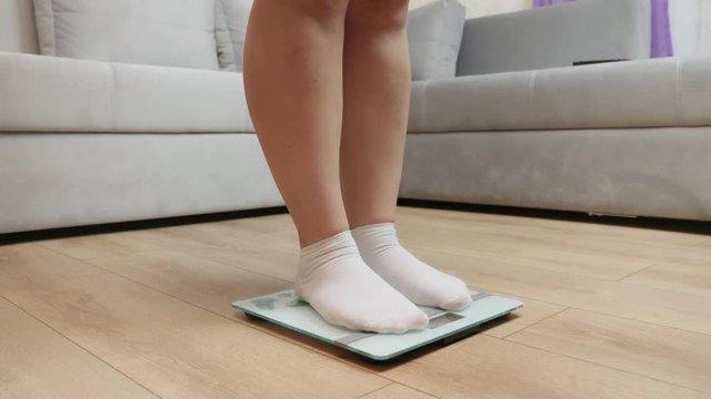 Women's feet in white socks on the floor scales. Weight control concept