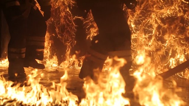 Firefighters run in flames and one of the firefighters falls into the fire