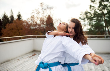 Young women practising karate outdoors on terrace. © Halfpoint