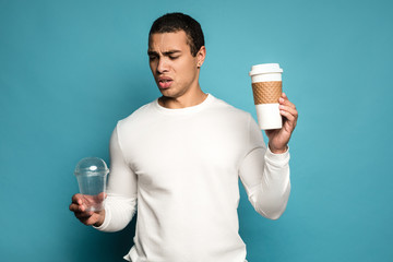 Environmental choice. Man holding reusable cup in one hand , in the other - plastic cup and looking...