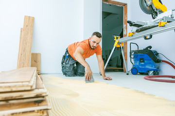 Craftsman is laying parquet flooring in a modern new building