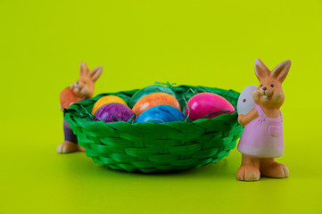 Osterhasen Familie vor Osternest mit bunten Eiern auf grünem Hintergrund