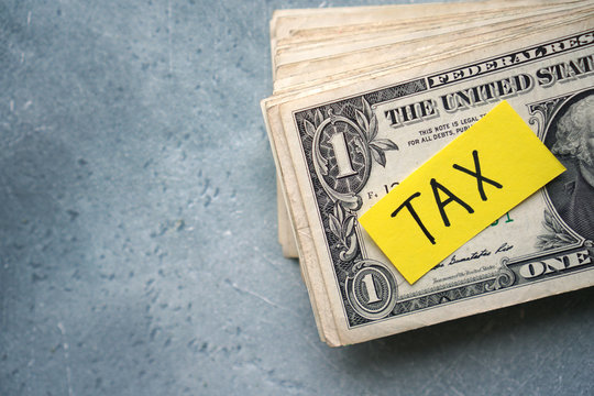 Taxes concept with one dolla bills stack and text Tax.