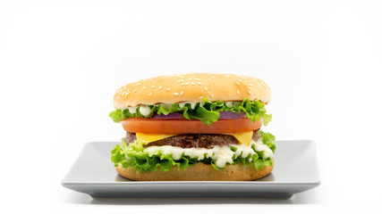 Homemade burger. Hamburger. Cheeseburger with lettuce, sauce, meat, cheese, tomato, onion and bread on  grey plate. Fast food. Lunch, dinner. White background, isolated. Copy space. Banner. 