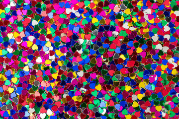 Background of heart shaped sparkles. Metallic scatter decorative texture. Multi colored foil confetti as backdrop for Valentine greeting card.
