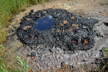 Active mud (clay and bitumen) volcano on the outskirts of the village Starunja in Carpathian. Spills of crude oil on the soil surface. Crater of the mud volcano.