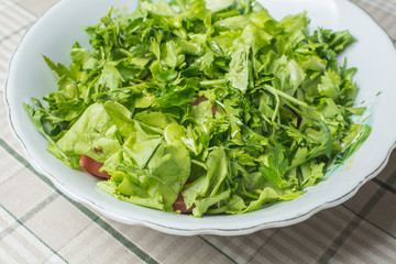 Fresh green salad of tomato and cucumber in plate on kitchen table.