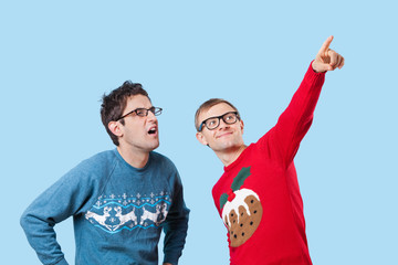 Two young men looking up against blue background