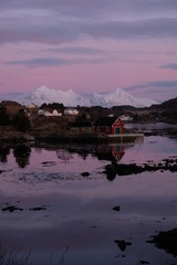Obraz premium Beautiful typical fishermans town located in Lofoten Islands, Norway. Rorbu houses in the bay of Ballstad. Pink sunrise in the background. 