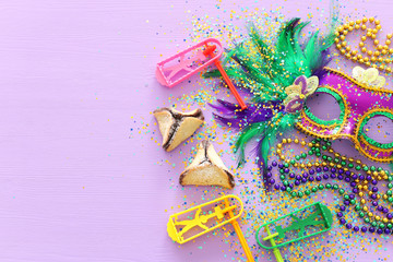 Purim celebration concept (jewish carnival holiday) over purple wooden background. Top view, Flat lay © tomertu