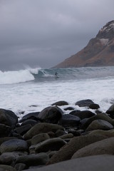 Surfer ride a wave in Unstad beach area which is known as an arctic surfing center located in Lofoten Islands in Northern Norway. 