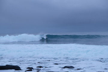 Surfer ride a wave in Unstad beach area which is known as an arctic surfing center located in Lofoten Islands in Northern Norway. 