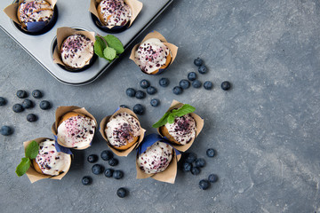 Blueberry muffins with white chocolate and fresh blueberries on stone grey table, top view