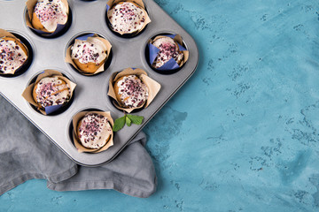 Blueberry muffins with white chocolate in the backing form on stone table, top view