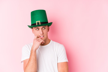 Young caucasian man celebrating saint patricks day relaxed thinking about something looking at a copy space.