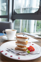 Close-up cake and coffee cup on a wooden table near the window