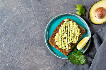 Avocado toast on whole grain bread, mashed avocado with sesame seeds and lime, healthy eating concept, top view
