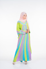 Beautiful female model wearing a pastel batik kaftan/caftan, a traditional dress for Muslim women isolated over white background. Stylish Muslim female hijab fashion lifestyle portraiture concept.