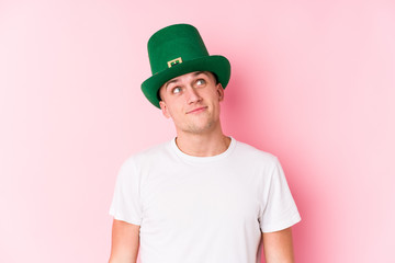 Young caucasian man celebrating saint patricks day dreaming of achieving goals and purposes