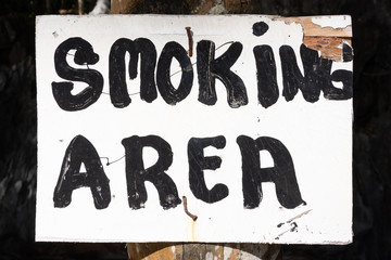 smoking area sign nailed to tree