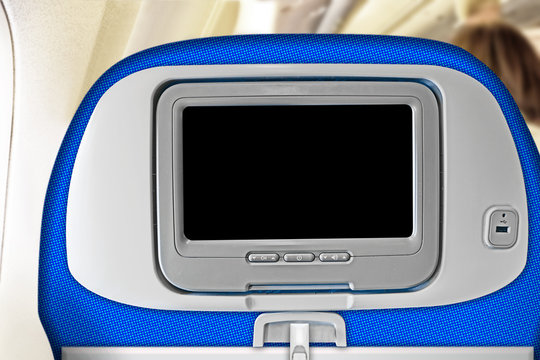 Travel Seat In Airplane Interior With Blank Inflight Entertainment System Screen In Headrest Against Plane Cabin Background. Back View Of Passenger Chair With Touchscreen. Copy Space Design Template