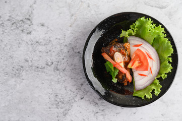 Appetizing Spicy Canned Sardine salad in spicy sauce in black ceramic bowl