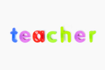 Alphabet magnets spelling 'teacher' over white background